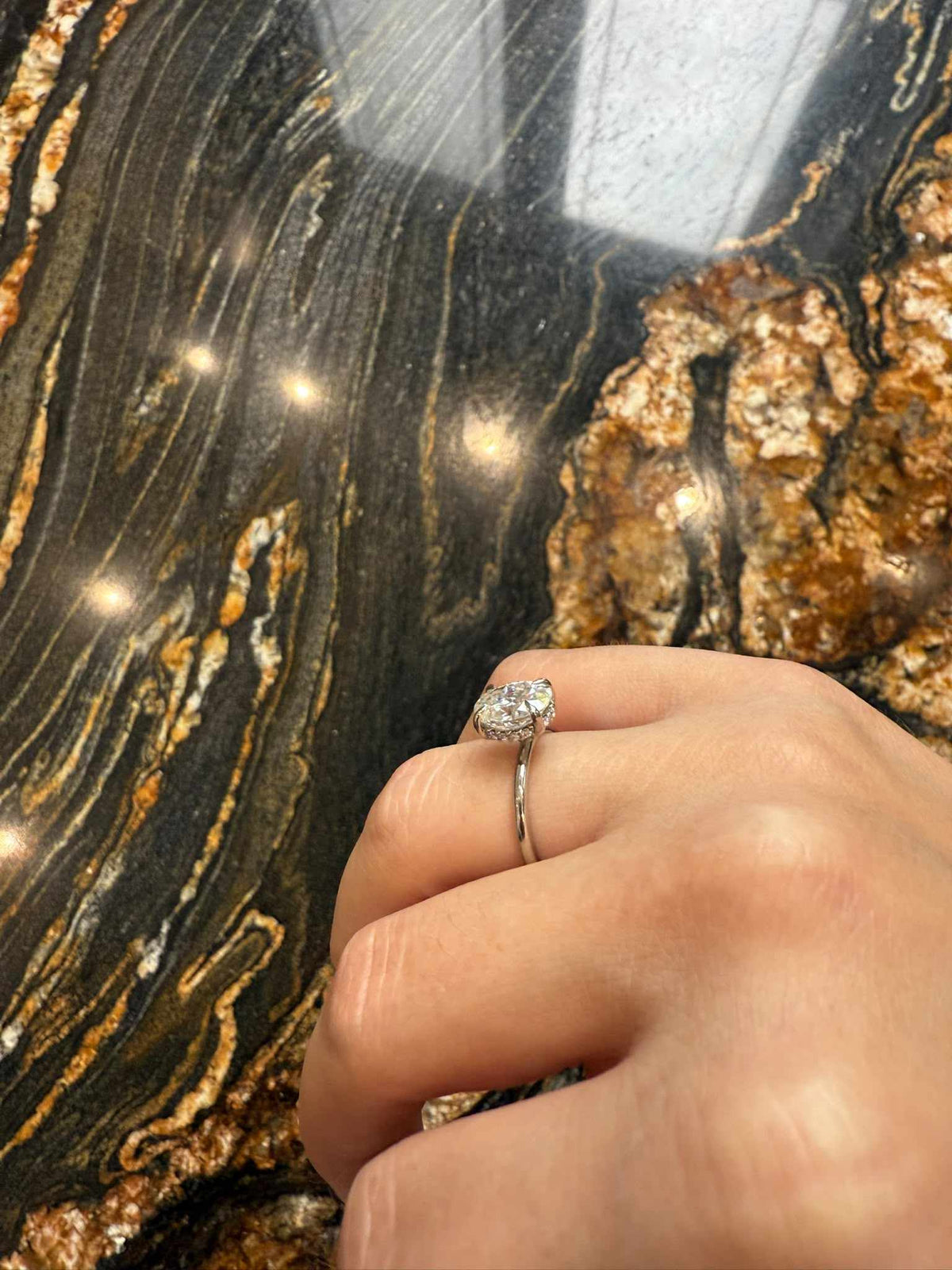 Inelul văzut din profil, purtat pe deget, fotografiat de noi. Aur Solid 14k Alb. – Inel de Logodnă Solitaire Oval cu Halo Ascuns din Aur 14k cu Diamant Creat în Laborator de 1.2 ct